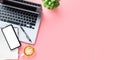 Office desk with laptop computer, Blank screen smart phone, cup of coffee, pen, Notebook on pink background Royalty Free Stock Photo