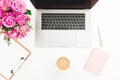 Office desk with laptop, pink roses bouquet, coffee mug, pink diary on white background. Flat lay. Top view Royalty Free Stock Photo