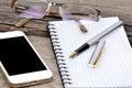 Office desk with notebook, fountain pen, eyeglasses and telephone