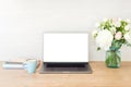 Office desk table with laptop computer with blank screen mockup, supplies, cup of coffee, flowers bouquet on wooden surface. Royalty Free Stock Photo