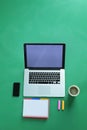 Office desk table with laptop, smart phone, cup of coffee and supplies, isolated on green background,flat lay Royalty Free Stock Photo