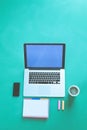 Office desk table with laptop, smart phone, cup of coffee and supplies, isolated on green background,flat lay Royalty Free Stock Photo