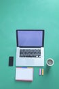 Office desk table with laptop, smart phone, cup of coffee and supplies, isolated on green background,flat lay Royalty Free Stock Photo