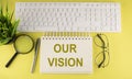Office desk table Top view with keyboard and notebook text OUR VISION on the yellow background Royalty Free Stock Photo