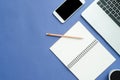 Flat lay top view mockup photo of working space with laptop, smartphone, coffee up and notebook on blue pastel background. Royalty Free Stock Photo