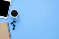 Flat lay top view mockup photo of working space with smart device, coffee cup and notebook on blue pastel background. Royalty Free Stock Photo