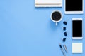 Office desk working space - Flat lay top view mockup photo of working space with tablet, phone, coffee cup and notebook on blue. Royalty Free Stock Photo