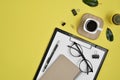 Office desk workspace with blank clip board, office supplies, pen, cactus, green leaf, coffee cup and eye glasses on yellow Royalty Free Stock Photo