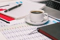 Office Desk workspace with coffee Cup, diary, Notepad and computer. Documents and tables with numbers. Business concept