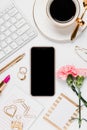 Cellphone with gold desk accessories and pink flowers in a white background Royalty Free Stock Photo