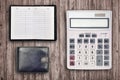 Office flat lay composition with calculator, address book and black purse on brown wooden table background with top view. Royalty Free Stock Photo