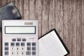 Office flat lay composition with calculator, address book and black purse on brown wooden table background with top view. Royalty Free Stock Photo