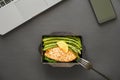 Office food delivery meal fish and vegetable lunch box at work on black table. Royalty Free Stock Photo