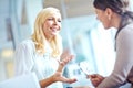 Office gossip. Two corporate women sharing a joke at the office.