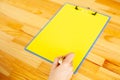 Office Hand Holding a Folder with a Yellow Color Paper and Pen on the Background of the Wooden Table. Copyspace. Place for Text. Royalty Free Stock Photo