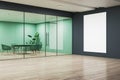 An office interior with a blank white poster mockup on a wall, modern glass partition, and the view of a room with furniture, on a Royalty Free Stock Photo