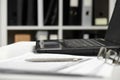 Office interior closeup. Table with laptop, documents, smartphone and eyeglasses