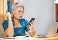 Office lifestyle portrait of attractive worried and stressed middle aged Asian woman using mobile phone at laptop computer desk Royalty Free Stock Photo