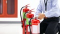 Office man checking the handle of the red fire extinguishers tank Royalty Free Stock Photo