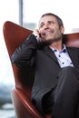 Office manager in red chair talking on cell-phone. Royalty Free Stock Photo