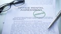 Office rental agreement approved, hand stamping seal on business document, close