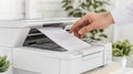 In an office setting, a businessman prints important documents using a multifunction laser printer, illustrating the Royalty Free Stock Photo