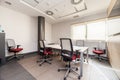 An office with several swivel chairs with a red seat, a wooden table, windows