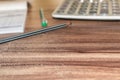 Office supplies, with a calculator, a ruler, a pen, and a notebook, are placed on the wood-grain table, taken from top view, and h