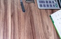 Office supplies, with a calculator, a ruler, a pen, and a notebook, are placed on the wood-grain table, taken from top view, and h