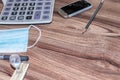 Office supplies, with a calculator, a ruler, a pen, and a notebook, are placed on the wood-grain table, taken from top view, and h