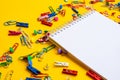 Office supplies of colored buttons and paper clips with empty note pad with copy space on yellow background Royalty Free Stock Photo