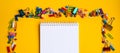 Office supplies of colored buttons and paper clips with empty note pad with copy space on yellow background Royalty Free Stock Photo