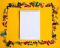 Office supplies of colored buttons and paper clips with empty note pad with copy space on yellow background Royalty Free Stock Photo