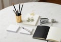 Office supplies on a round white marble table include a gold holder with pencils and a pen, a small Royalty Free Stock Photo