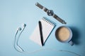 Office supplies. Top view on opened notebook, pen, headphone, laptop and cup of coffee on blue Royalty Free Stock Photo