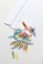 Office supplies, white envelope, colorful paper clips lying on white table Royalty Free Stock Photo