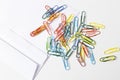 Office supplies, white envelope, colorful paper clips lying on white table Royalty Free Stock Photo
