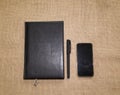 Office supply collection - notebooks and phone on brown burlap Royalty Free Stock Photo
