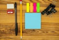 Office supply collection on a wooden desk background. Pencil, pen, scraper, eraser, bookmarks, paper clips and blank sticky notes Royalty Free Stock Photo