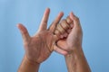 Office syndrome concept. Ring finger is massaged and stretched after working. Close up shot isolate on blue background. Forehand