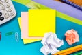 Office table desk with set of colorful supplies, white blank note pad, cup, pen, pc, crumpled paper, flower on blue Royalty Free Stock Photo