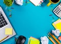 Office table desk with set of colorful supplies, white blank note pad, cup, pen, pc, crumpled paper, flower on blue Royalty Free Stock Photo