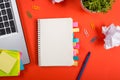 Office table desk with set of colorful supplies, white blank note pad, cup, pen, pc, crumpled paper, flower on red Royalty Free Stock Photo