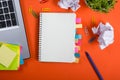 Office table desk with set of colorful supplies, white blank note pad, cup, pen, pc, crumpled paper, flower on red Royalty Free Stock Photo