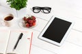 Office table desk with set of supplies, white blank notepad, cup, pen, tablet, glasses, flower on white background. Top Royalty Free Stock Photo