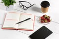 Office table desk with set of supplies, white blank notepad, cup, pen, tablet, glasses, flower on white background. Top Royalty Free Stock Photo