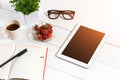 Office table desk with set of supplies, white blank notepad, cup, pen, tablet, glasses, flower on white background. Top Royalty Free Stock Photo