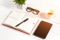 Office table desk with set of supplies, white blank notepad, cup, pen, tablet, glasses, flower on white background. Top Royalty Free Stock Photo