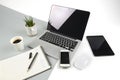 Office table with laptop computer, notebook, digital tablet and smartphone on modern two tone white and grey background