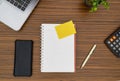 An office table working enviroment. Notepad, sticky note, pen plant, calculator and a lap top on a brown striped zebrawood design Royalty Free Stock Photo